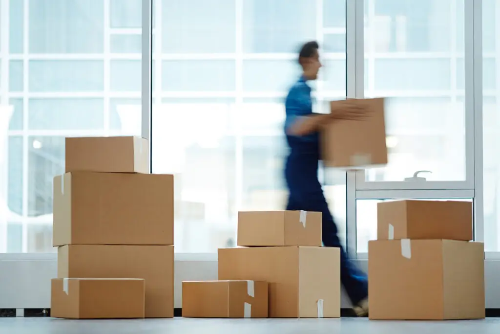 UK parcel courier carrying packages for next-day delivery service in office environment.