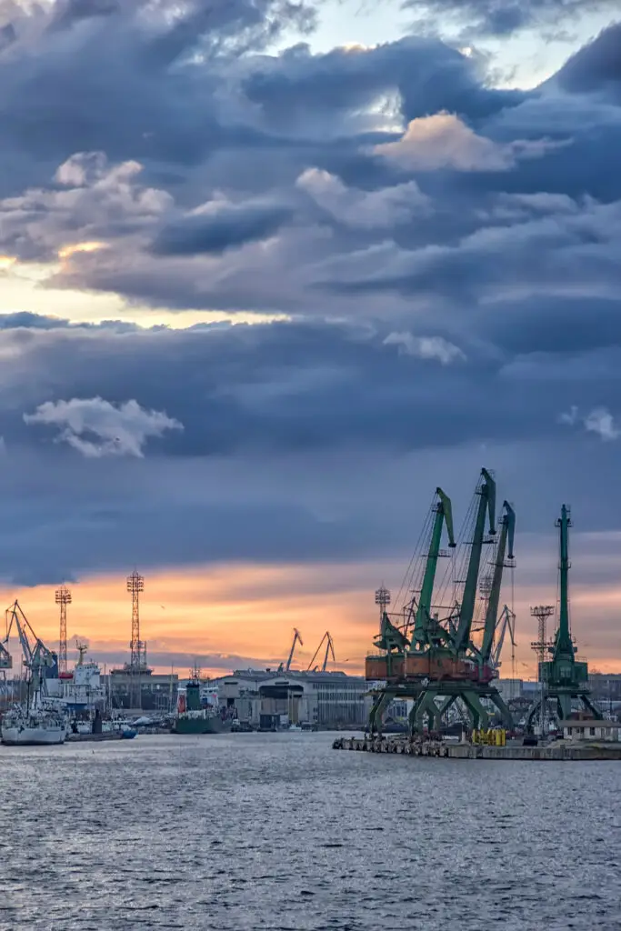 Cargo port with cranes and shipping vessels at sunset, illustrating maritime infrastructure and global logistics services in action.