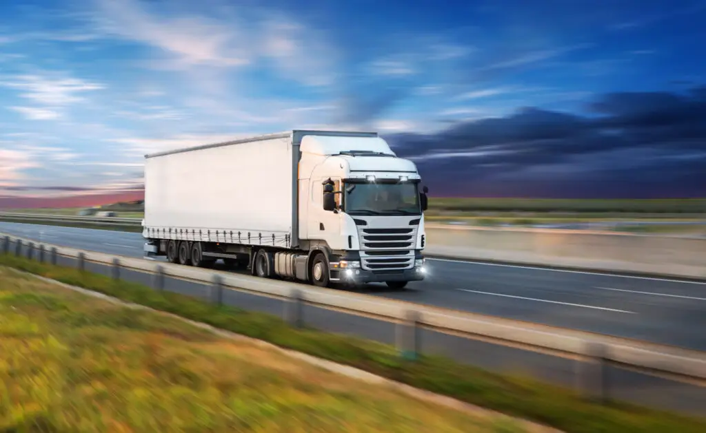 Road freight truck transporting container collection on highway at sunset, illustrating efficient trucking logistics and long-distance transport services.