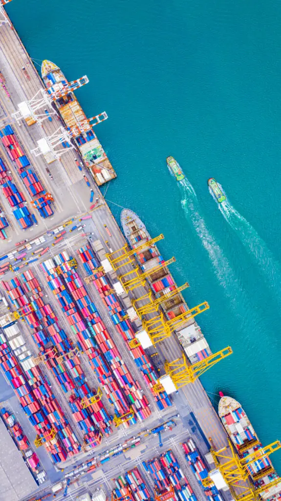 Aerial view of a busy cargo port with container ships and cranes – representing global logistics and UK export services.
